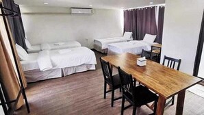 A hotel room with two single beds, a wooden table, and a chair.