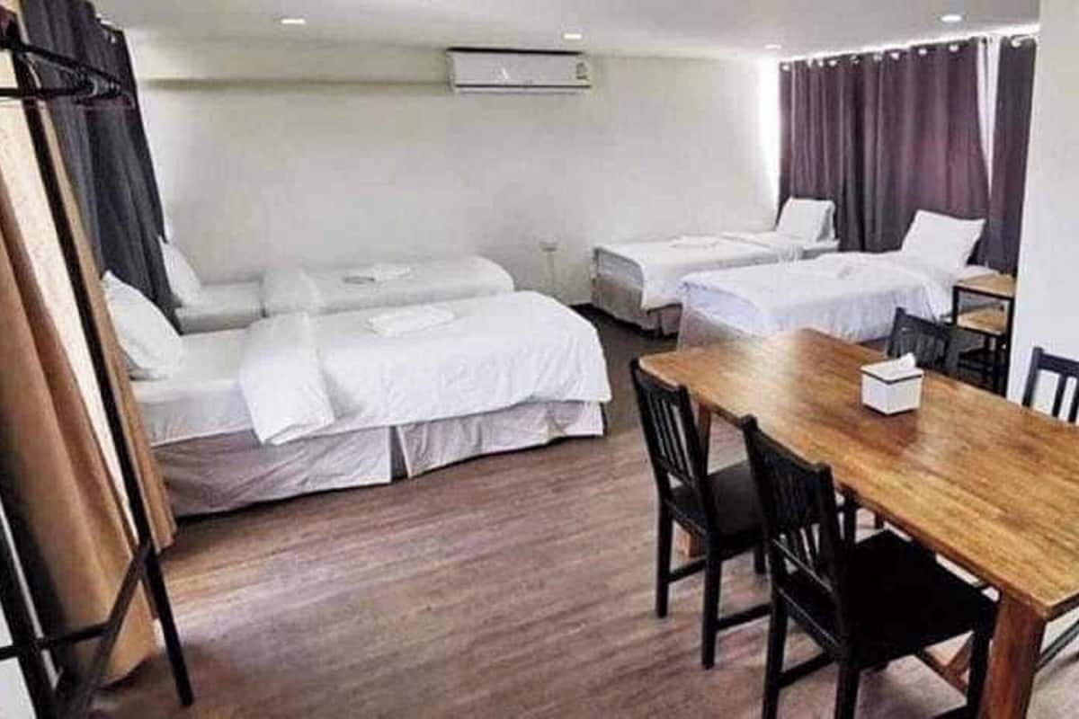 Una habitación de hotel con dos camas individuales, una mesa de madera y una silla.