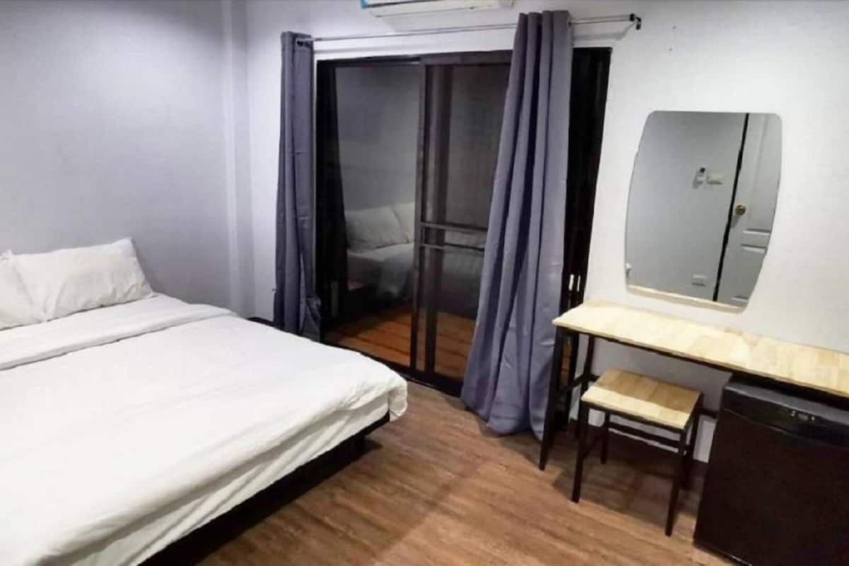 Un dormitorio con cama, escritorio, silla, espejo y puerta corredera.