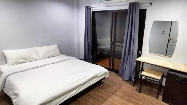 A bedroom with a bed, a desk, a chair, a mirror, and a sliding door.