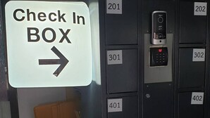 A check-in box sign with a directional arrow, a series of numbered lockers, and a piece of paper with hotel contact information.