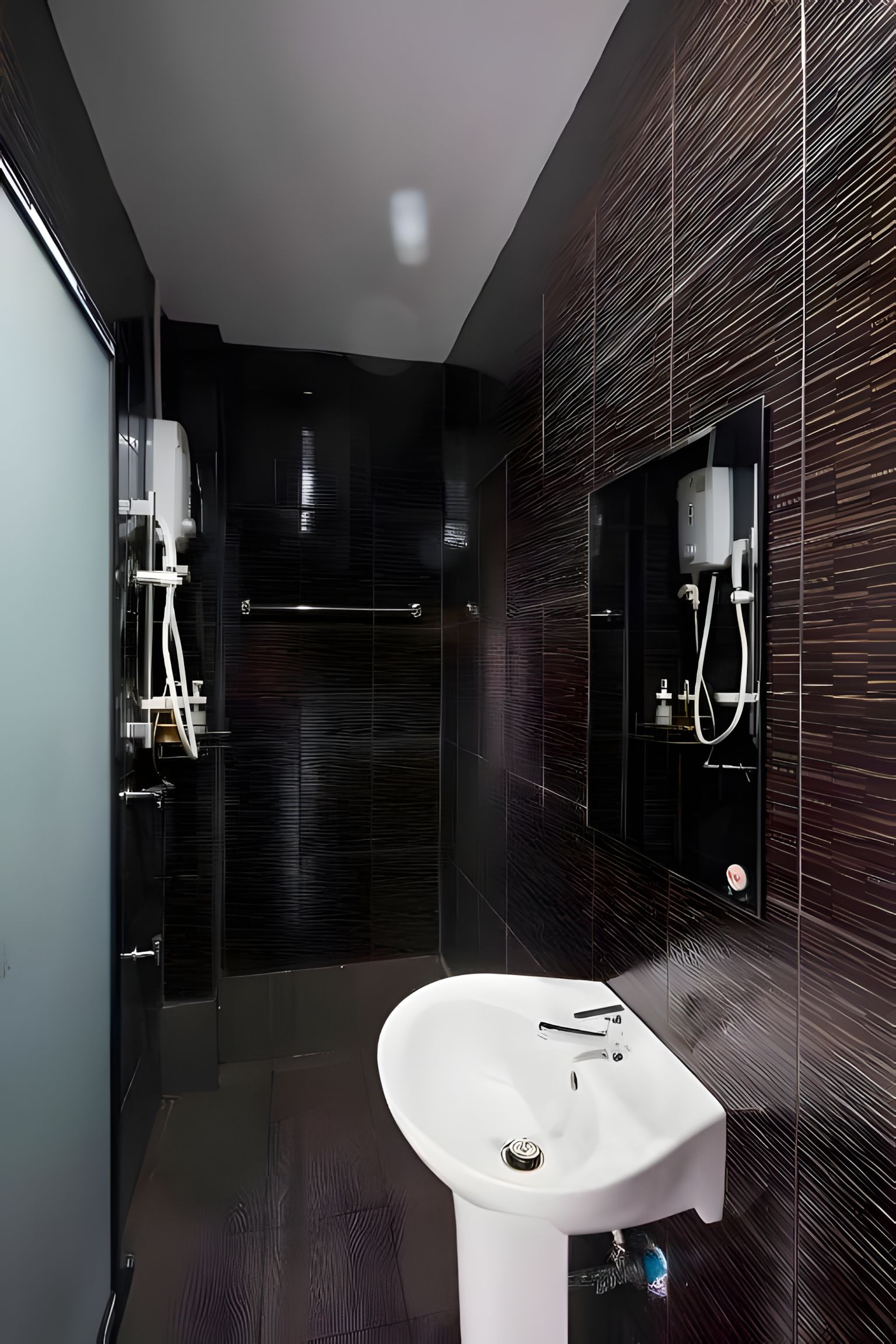 A modern bathroom with a white sink, dark tiled walls, and a mirror.