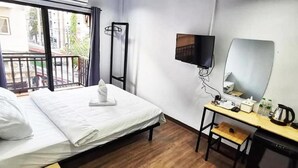 A hotel room with a bed, a desk, a TV, and a window with a view of buildings.