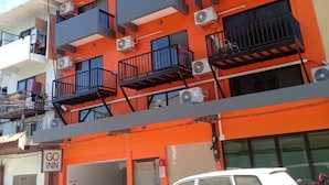 A multi-story building with balconies, air conditioning units, and a sign for 'GO INN'.