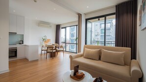 A modern living room with a sofa, coffee table, and dining area. - Mia Apartments by XÔI Residences (Hanoi)