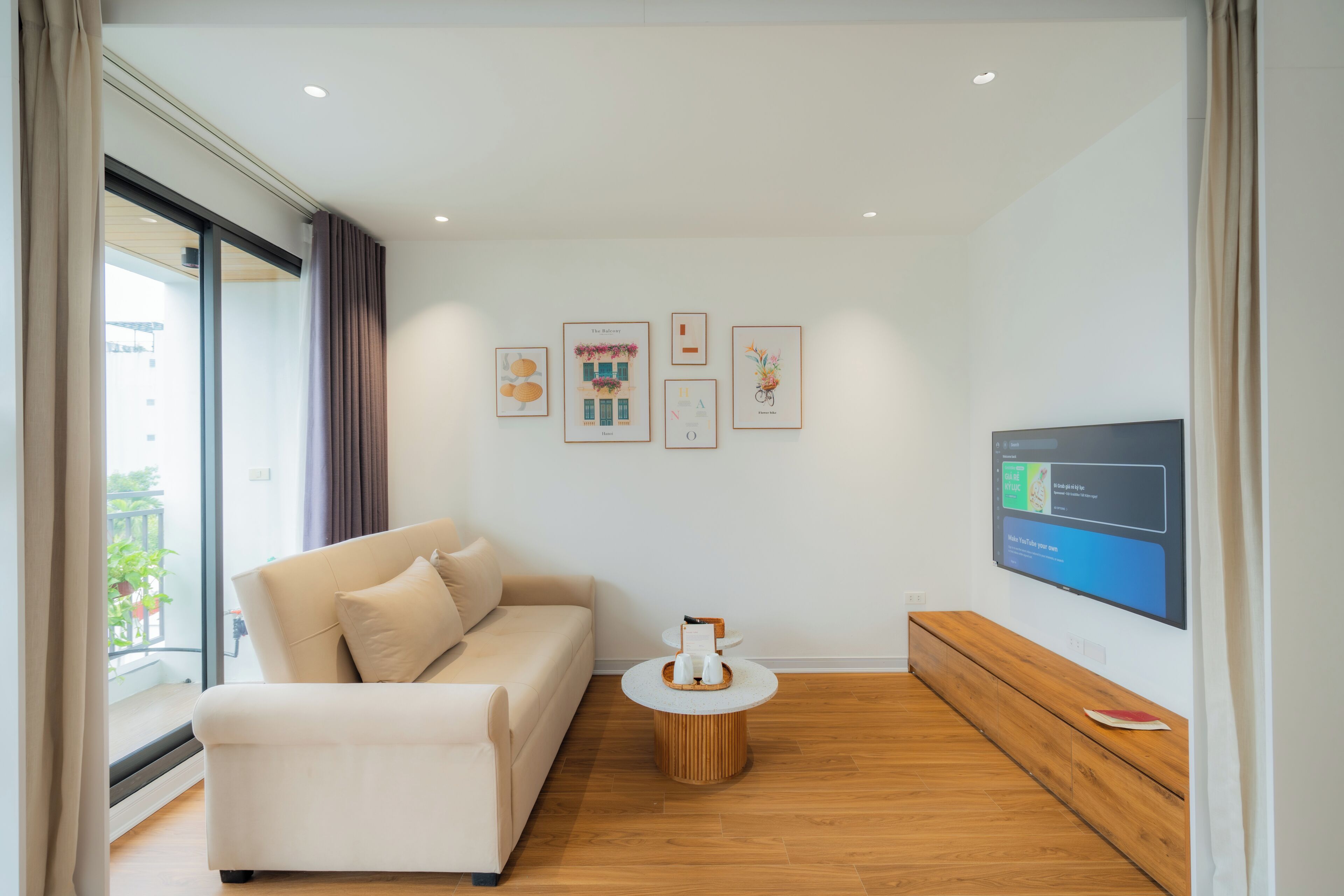 A modern living room with a sofa, a coffee table, and a flat-screen TV mounted on the wall.