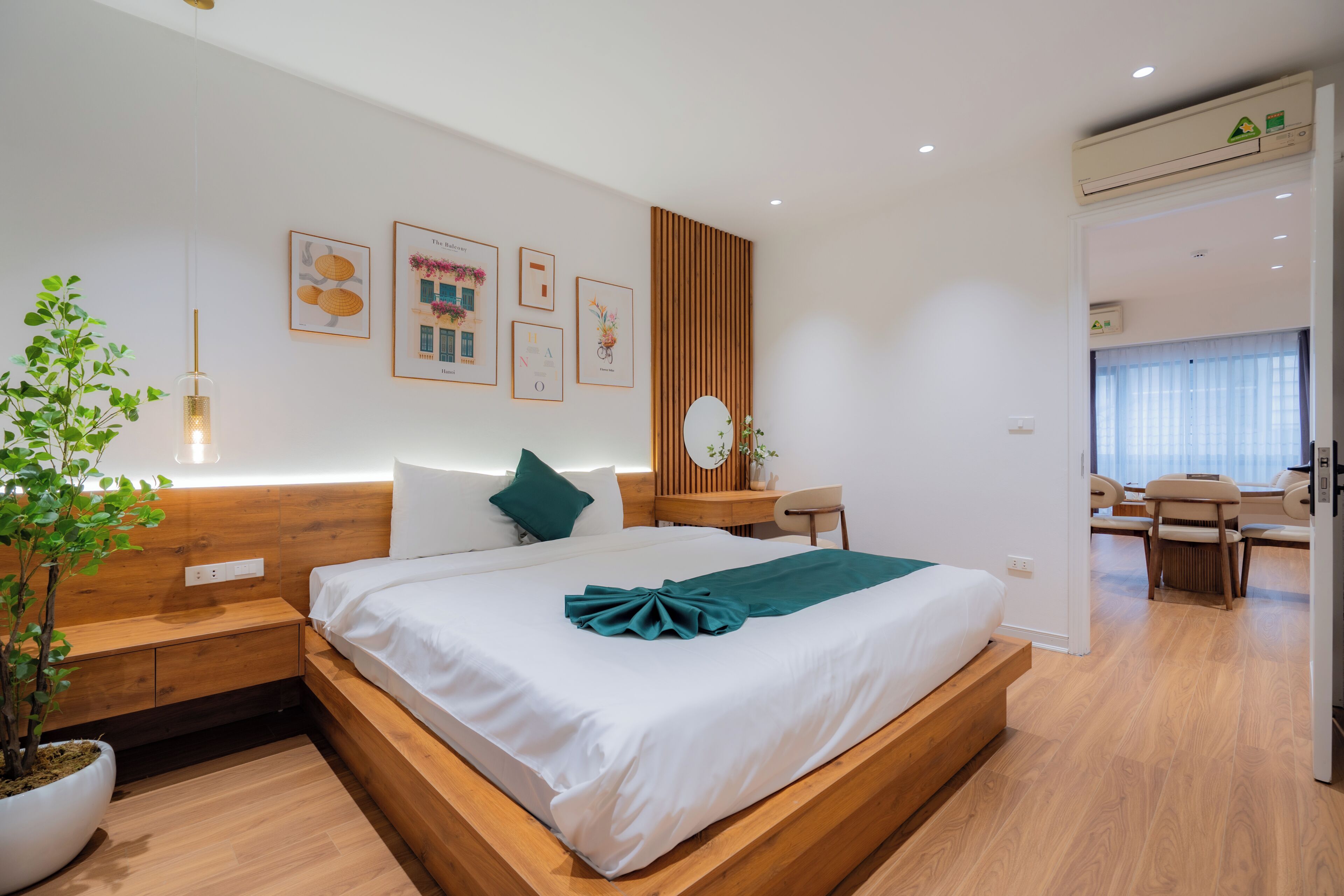 Een moderne hotelkamer met een houten bed, nachtkastje, bureau en een potplant.
