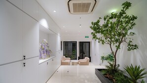 A modern lobby with a reception desk, seating area, and indoor plants. - Mia Apartments by XÔI Residences (Hanoi)