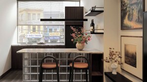 A modern kitchen with a built-in island, bar stools, and a window with a city view. - Miracle Boutique - Near Tan Dinh Church (Ho Chi Minh City)