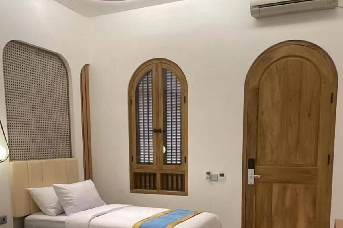 A bedroom with two beds, a wooden door, and an air conditioning unit.