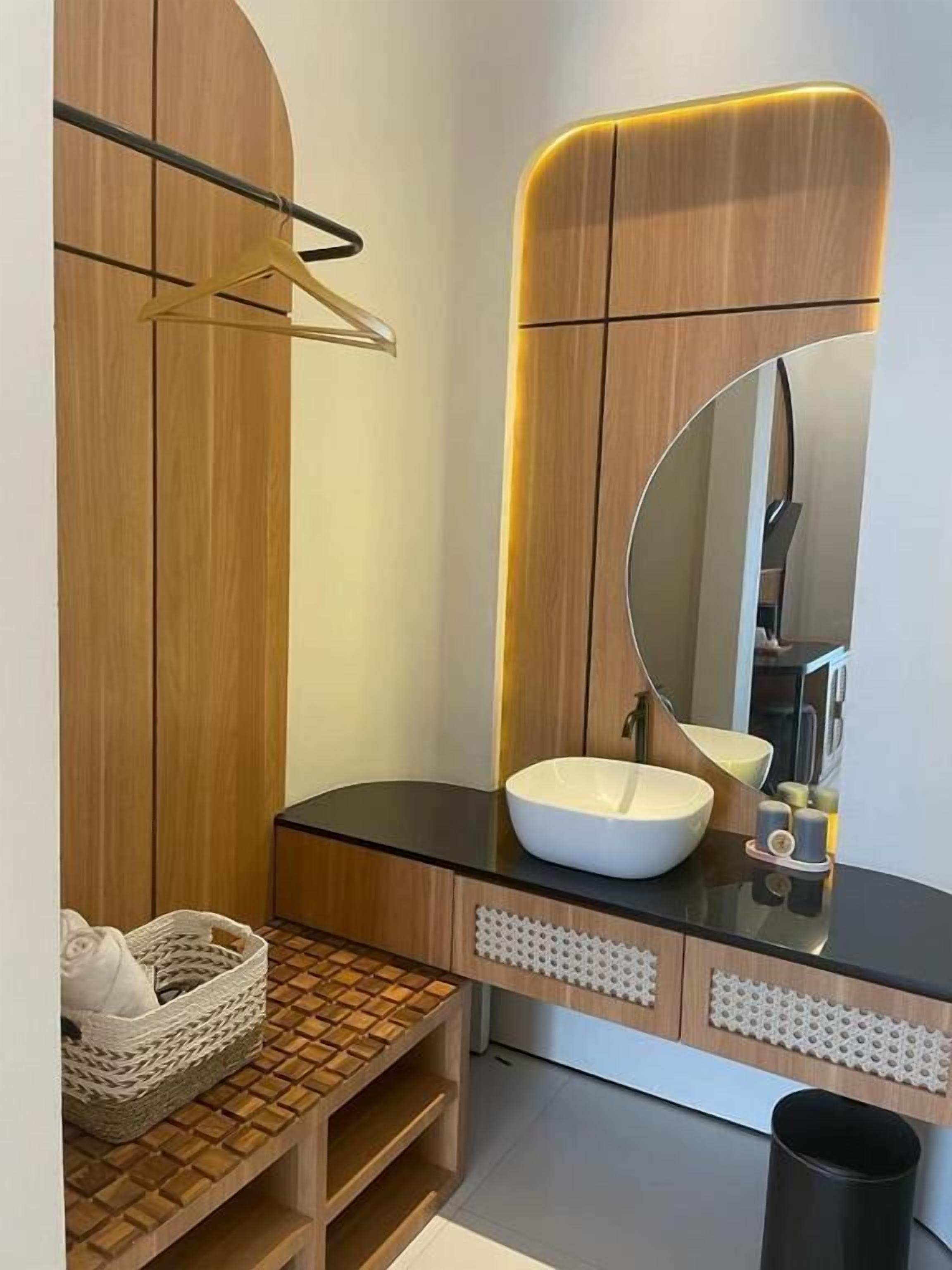 A modern bathroom with a wooden vanity, a large mirror, and a white sink.