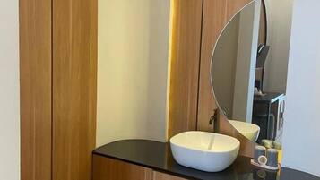 A modern bathroom with a wooden vanity, a large mirror, and a white sink.