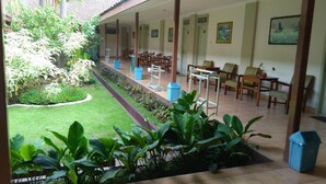 Un espace extérieur abrité, agrémenté d’un jardin, de chaises et de tables disposées pour les repas ou la détente.