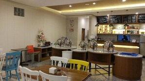 Un restaurant avec des tables rondes, des chaises, un comptoir et un tableau affichant le menu.