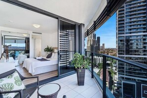 Ein moderner Balkon mit Bett, Sitzgelegenheit und Topfpflanze.