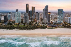 A coastal cityscape with high-rise buildings, a beach, and ocean waves. - Peppers Retreat Atop The Broadbeach Skyline (Gold Coast)