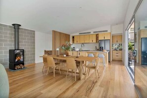 Eine moderne Küche mit einer zentralen Kochinsel, Holzschränken und einem eingebauten Holzofen.