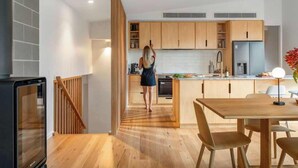 Una cocina moderna con armarios de madera, un comedor con mesa y sillas, y una escalera que lleva a un nivel superior.