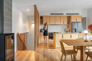 Eine moderne Küche mit Holzausstattung, ein Essbereich mit Tisch und Stühlen sowie eine Treppe, die zu einer oberen Ebene führt.