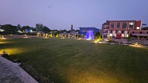 A grassy field with a fountain, buildings in the background, and a clear sky. - BALAJI HOTEL AND RESTAURANT (Uluberiya)