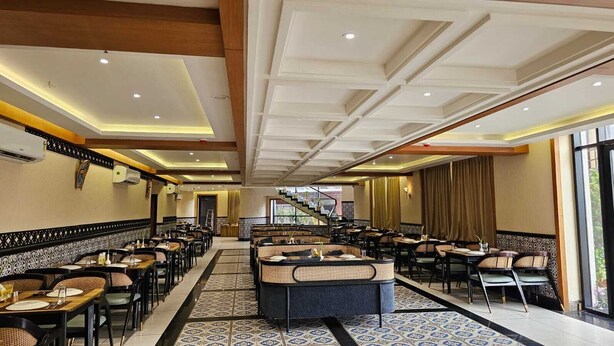A spacious restaurant with high ceilings, patterned flooring, and a central seating area. - BALAJI HOTEL AND RESTAURANT (Uluberiya)