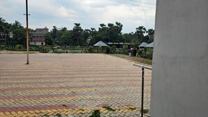 A paved outdoor area with a fence, a building labeled 'HOTEL BALAJI WITH RAMGON,' and some greenery in the background. - BALAJI HOTEL AND RESTAURANT (Uluberiya)