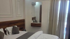 A hotel room with a large bed, a bedside table, a mirror, and a window with curtains. - HOTEL R R TRIPATHI (Faizabad)