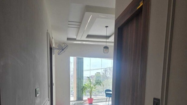 A hallway with marble flooring, a wooden door, and a view of the outdoors. - HOTEL R R TRIPATHI (Faizabad)