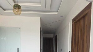 A hallway with a marble floor, a wooden door, and a hanging light fixture. - HOTEL R R TRIPATHI (Faizabad)