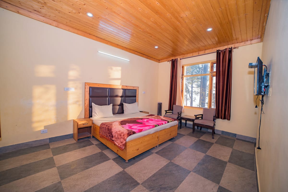 A bedroom with a large bed, a desk, and a chair.