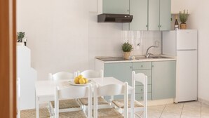 Une cuisine compacte avec des meubles blancs, une cuisinière encastrée et un évier.