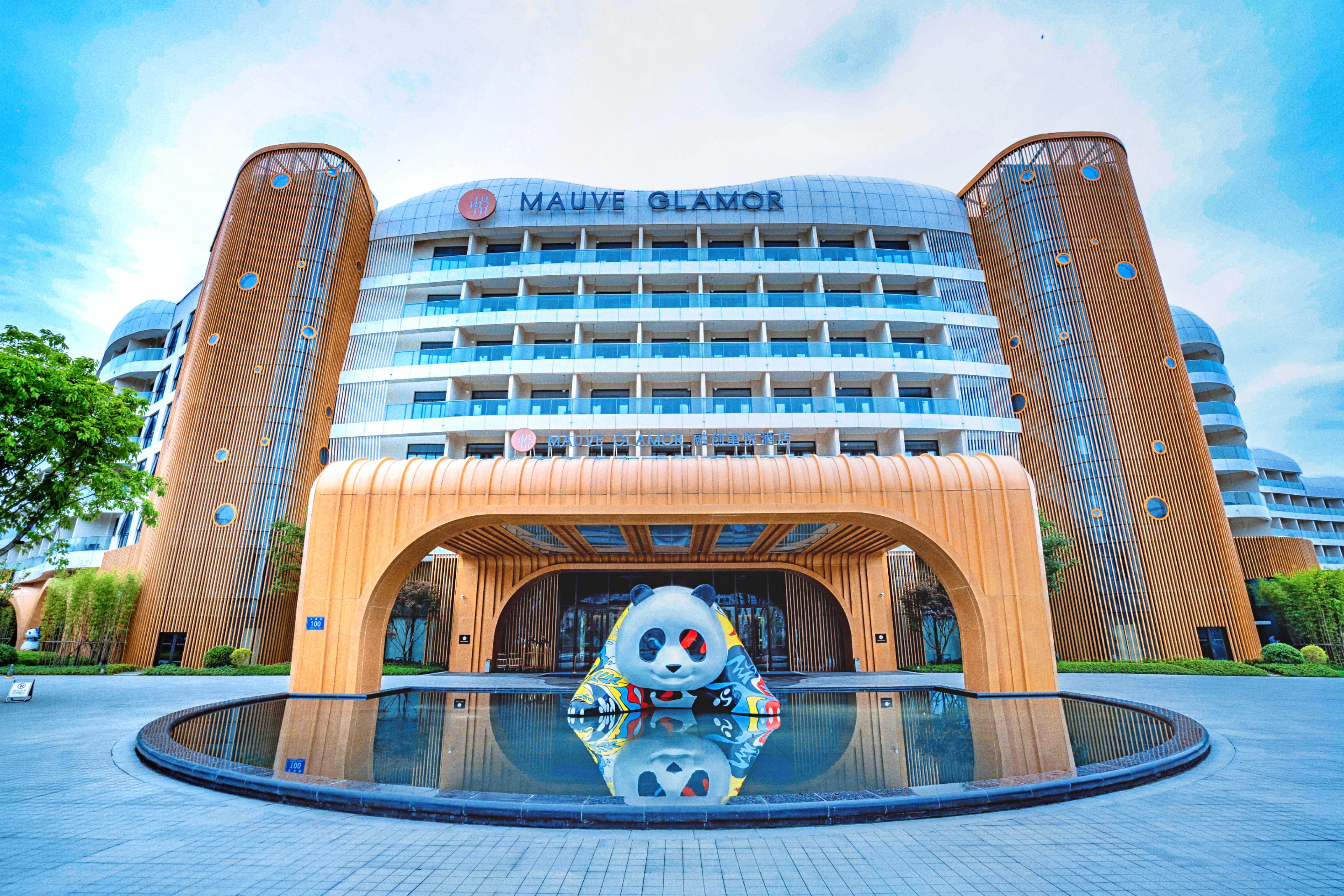 A hotel with a distinctive panda sculpture in front, a large glass facade, and a modern architectural design.