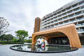 A modern building with a large panda statue at the entrance, a reflective pool, and a clear sky. - Mauve Glamor Chengdu (Chengdu)