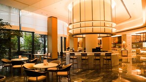 A modern lobby with a central bar area, seating arrangements, and a large, circular light fixture. - Mauve Glamor Chengdu (Chengdu)