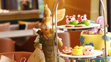 A tiered dessert stand with various sweets, a duck figurine, and a small duck-shaped container on a table.