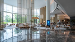 A spacious lobby with a high ceiling, large windows, and a central seating area. - Mauve Glamor Chengdu (Chengdu)