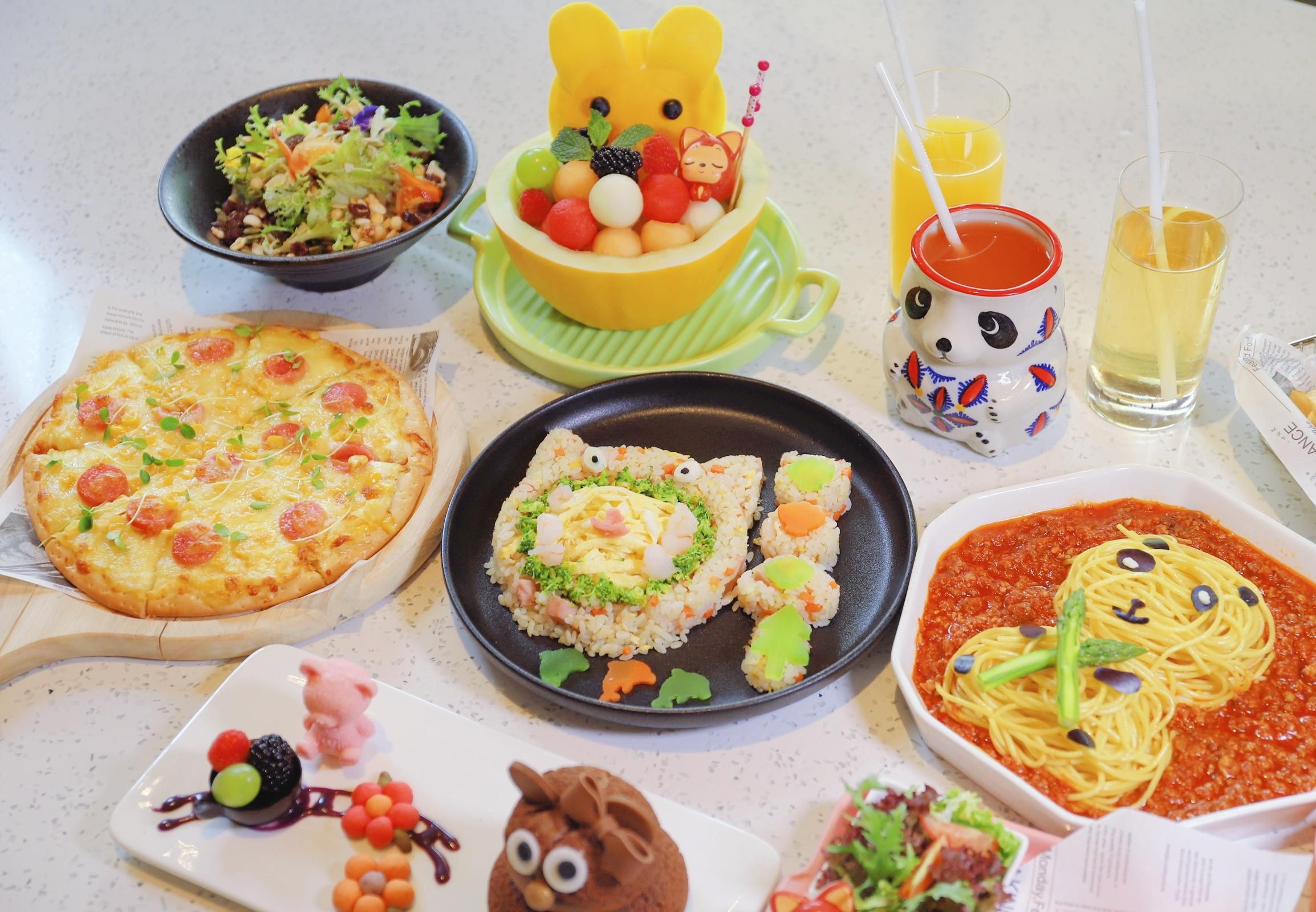 A variety of food items on a table, including pizza, sushi, pasta, and a bowl of fruit.