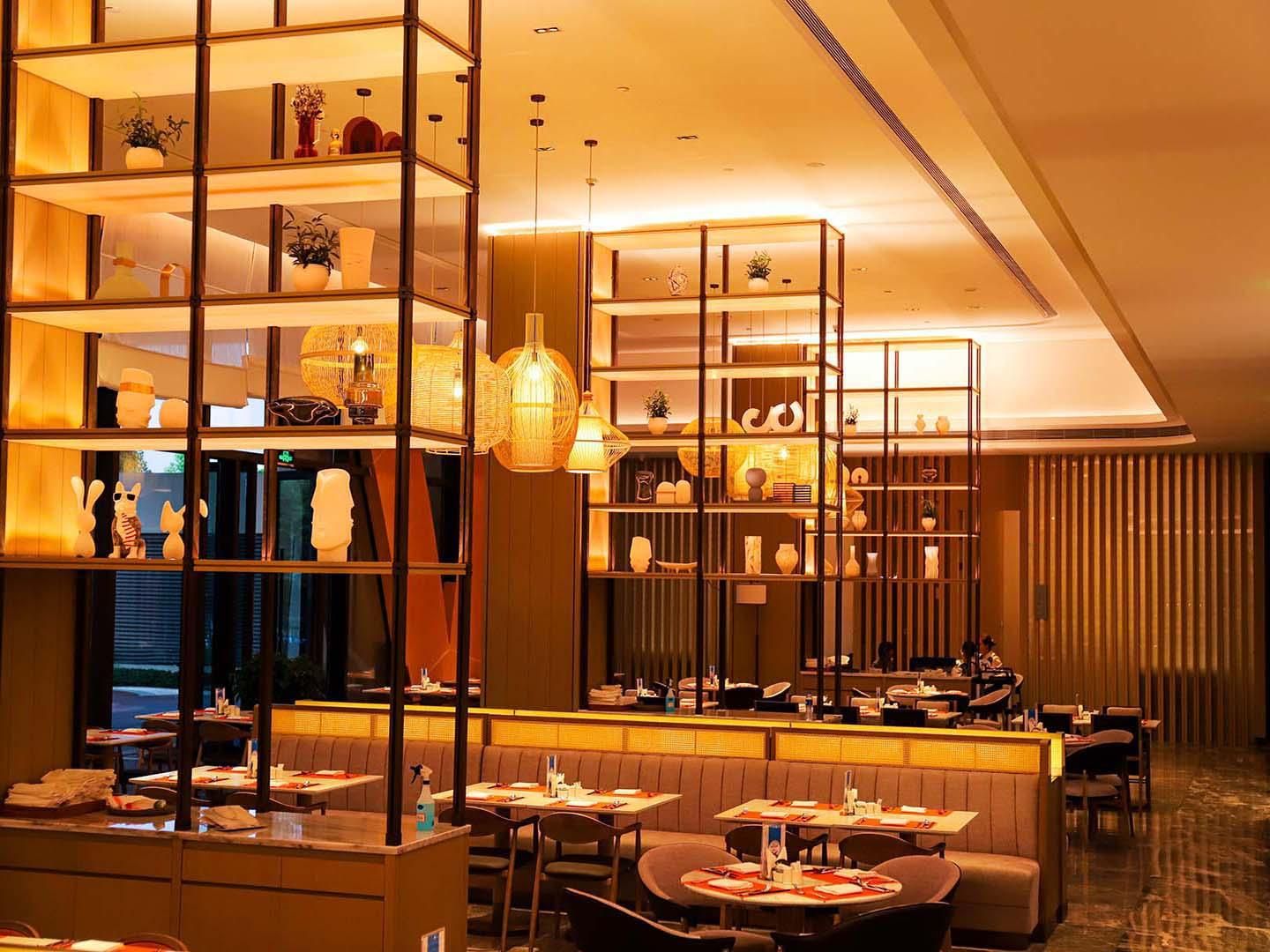 En restaurant med flere spiseområder, en bar og reoler med diverse genstande.