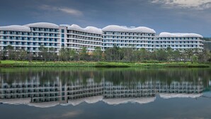A modern hotel with multiple floors, large windows, and a reflection in the water. - Mauve Glamor Chengdu (Chengdu)