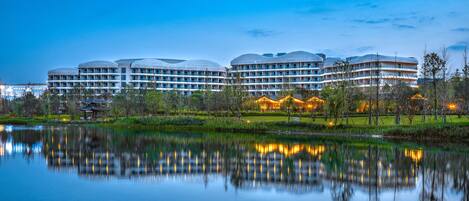 A modern hotel with multiple dome-shaped buildings, a reflective lake, and a well-maintained garden.