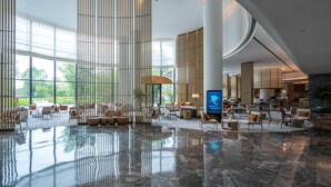 A spacious lobby with a high ceiling, large windows, and a central seating area. - Mauve Glamor Chengdu (Chengdu)