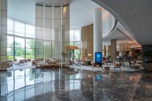 A spacious lobby with a high ceiling, large windows, and a central seating area. - Mauve Glamor Chengdu (Chengdu)