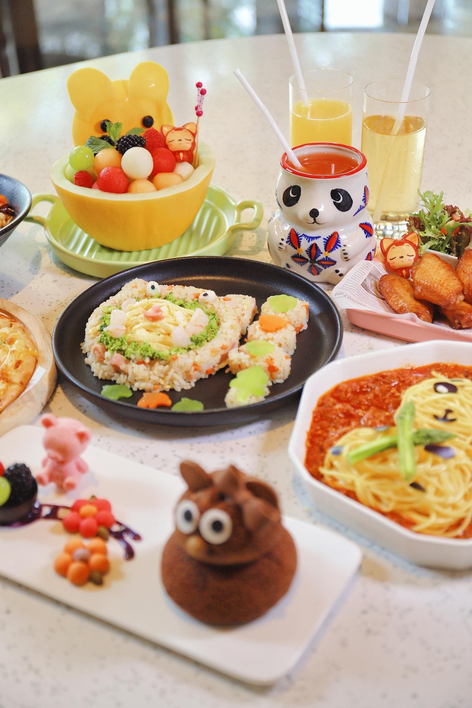 A table with various dishes, including a bear-shaped dessert, a plate of rice with vegetables, and a bowl of soup.