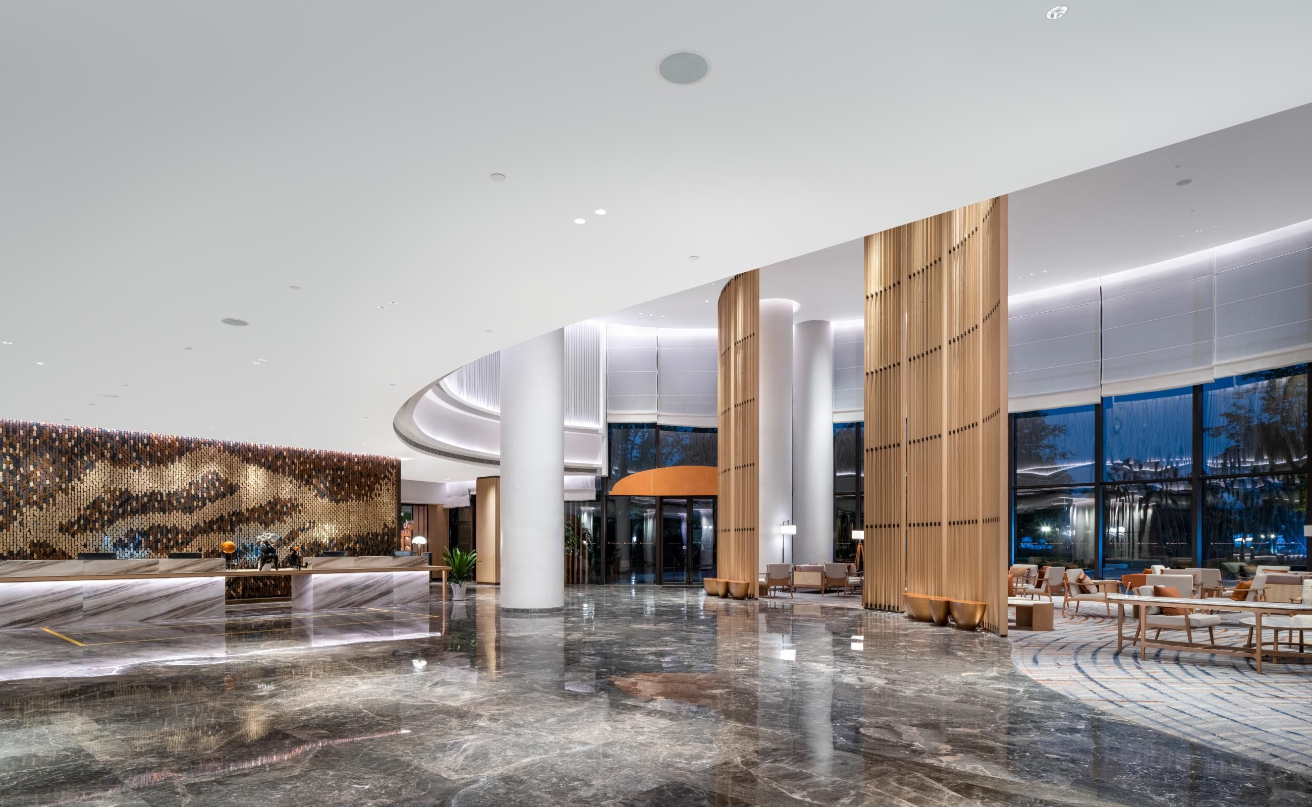 A spacious lobby with a reception desk, seating area, and large windows.