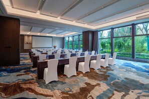 A conference room with a large table, white chairs, and a carpeted floor. - Mauve Glamor Chengdu (Chengdu)