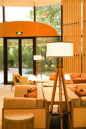A modern lobby with a seating area, a lamp, and a view of the outdoors. - Mauve Glamor Chengdu (Chengdu)