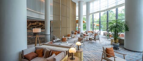 A spacious lobby with seating areas, a large plant, and a modern design.