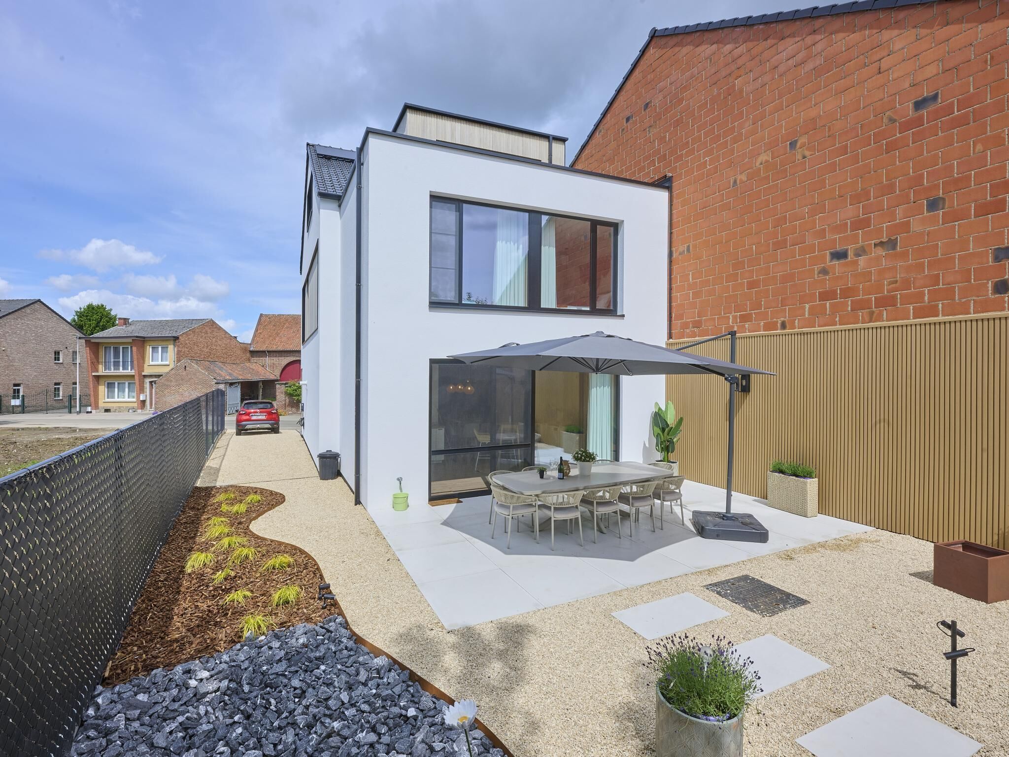 A modern house with a patio, a dining area, and a garden.