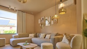 A modern living room with a sectional sofa, a round coffee table, and two pouf-style chairs.