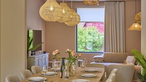 A dining area with a wooden table set for six, surrounded by cushioned chairs.